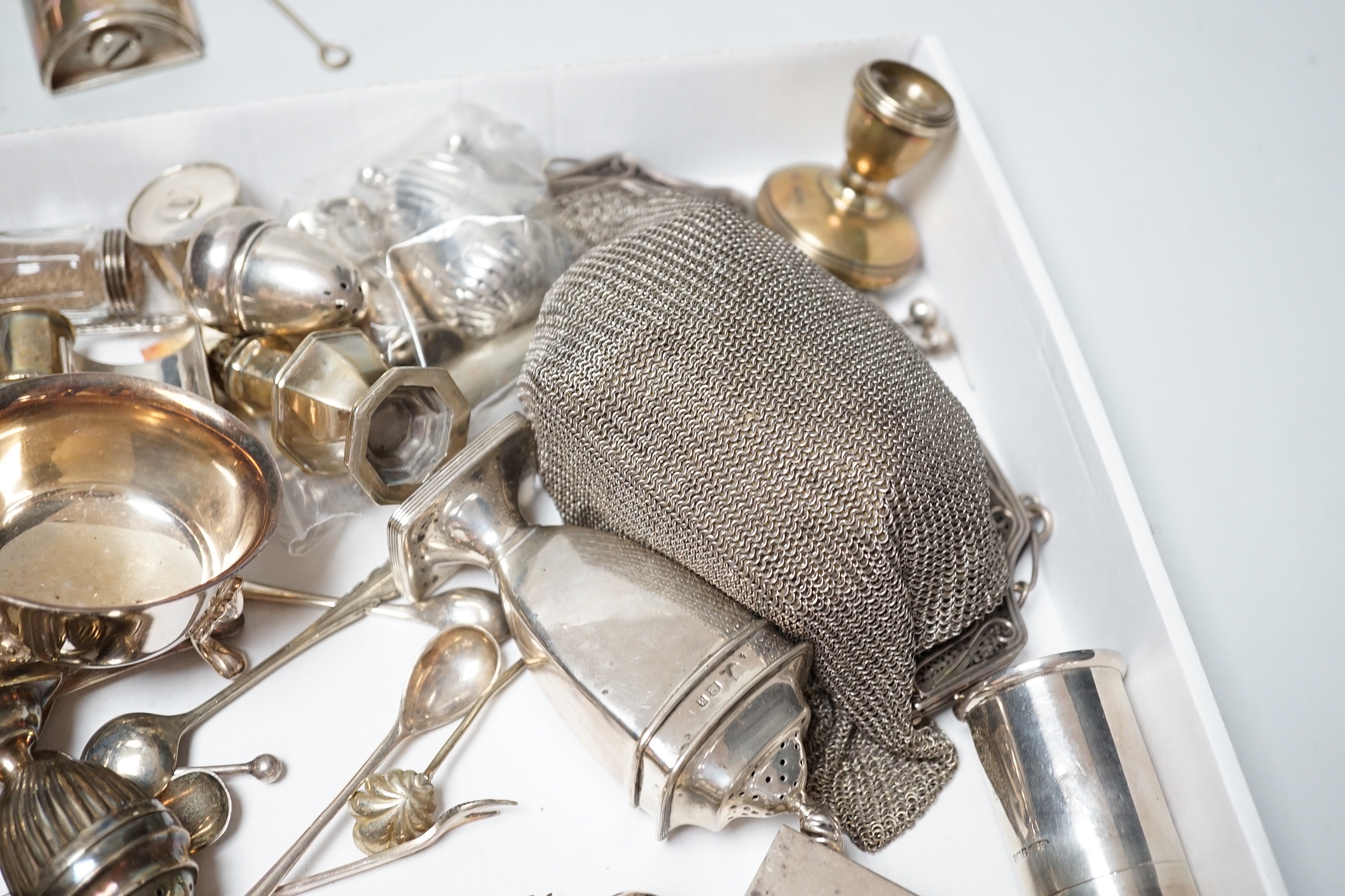 A collection of assorted small silver including condiments, spoons, egg cup, pill box, comb, Tiffany & Co pen, dwarf candlesticks, and other items including a plated evening bag and African trowel.